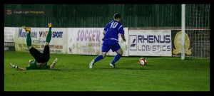 Brighouse Town goalkeeper Jacob Giles is left on his back and after being tackled in possession of the ball by Stephen Bromley, who was able to tap home into the empty net during Harrogate Railway's 2-1 defeat to Brighouse Town in the West Riding County Cup. Photo: Caught Light Photography