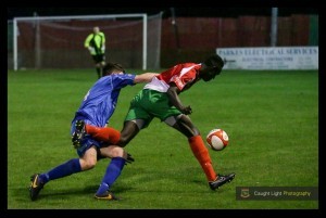 Young Harrogate Railway striker Lamin Colley takes on the Clitheroe defender. Photo: Caught Light Photography