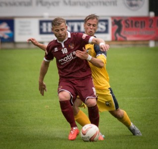Trialist B - Danny Frost - holds the ball up as Tadcaster's Jordan Armstrong bears down