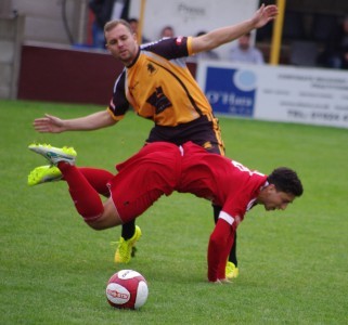 Ossett Town midfielder Sam Akeroyd falls under a challenge